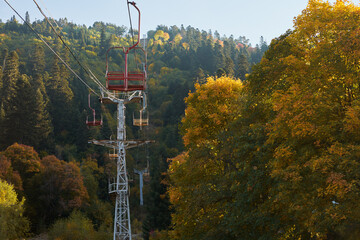 A cable car double chairlift in the mountains on an early fall morning with many chairs in the air.