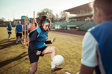 A focused soccer player maneuvers the ball past a defender during team practice
