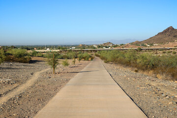 Dreamy Draw preserve dirt hiking trails and paved bike path near Arizona State Route 51 highway with a distant view of Phoenix downtown, Arizona