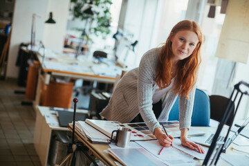 Young female designer working in a office and looking at the camera