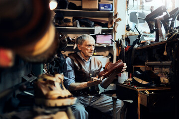 Elderly craftsman inspecting a handcrafted shoe in his traditional workshop