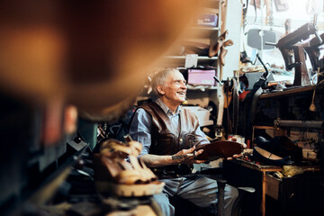Elderly shoemaker working in a shop