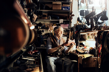 Elderly craftsman inspecting a handcrafted shoe in his traditional workshop