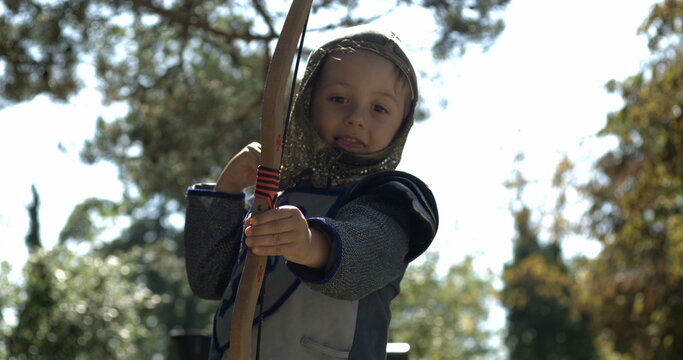 Small boy wearing medieval costume throwing arrow holding bow outside captured