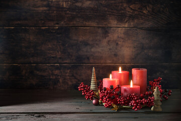 Third advent wreath with red candles, three are lit, decoration with berries, Christmas balls and small wooden trees, dark rustic background, copy space, selected focus - 668841307