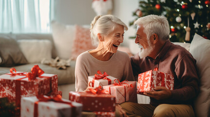 Senior Couple Exchanging Gifts As They Celebrate Christmas At Home With Family - obrazy, fototapety, plakaty