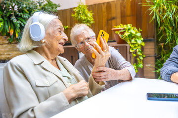 Seniors listening music with mobile and headphones in a geriatric