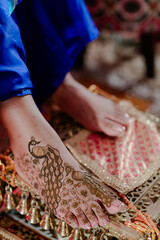 Mehndi master drawing henna tattoo on female