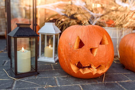 Sunny Halloween Day with a Carved Pumpkin and Glowing Lanterns on a Sidewalk