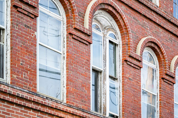 Old arched windows in a multi-story brick building with relief masonry of cornices and arches