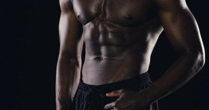 Closeup, abs and man with bodybuilding, stomach and challenge on a dark studio background. Person, model or athlete with self care, aesthetic or fitness with workout, progress or training with health