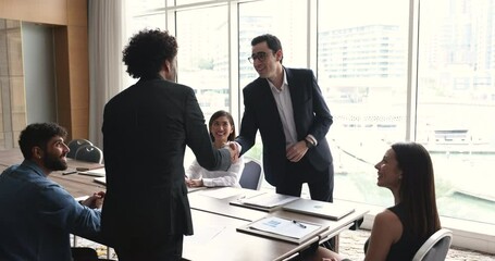 Two smiling businessmen leaders in formal suits shake hands finish meeting in office with partners, closing commercial profitable deal, express respect for good job and cooperation. Business etiquette