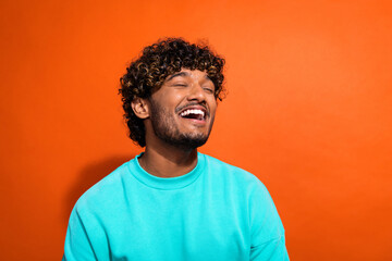 Photo of carefree overjoyed person closed eyes toothy smile good mood laughing isolated on orange color background