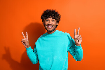 Photo of positive nice person toothy smile hands fingers demonstrate v-sign isolated on orange color background