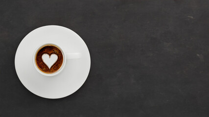 Morgendlicher Genuss: Eine dampfende Kaffeetasse mit einem zarten Schaumherz auf einem dunklen Tisch – der perfekte Moment der Entspannung und Sinnesfreude