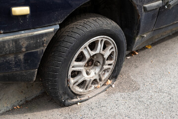 Fototapeta na wymiar Close-up damaged tire. The wheel of car tire leak. Flat tire waiting for repair. Abandoned car in the parking lot.