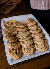 white rectangular platter of three rows of fresh baked chocolate chip cookies