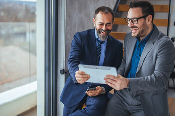 Two happy business colleagues at meeting in modern office interior. Successful mature boss in a...