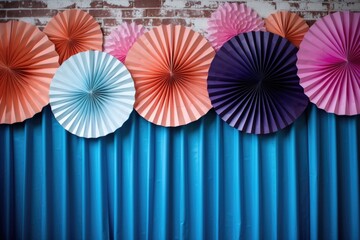 orange, pink and blue paper fans on the wall