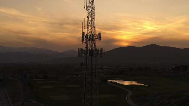 Aerial flyover view of silhouette of cell tower at sunset / Cedar Hills, Utah, United States