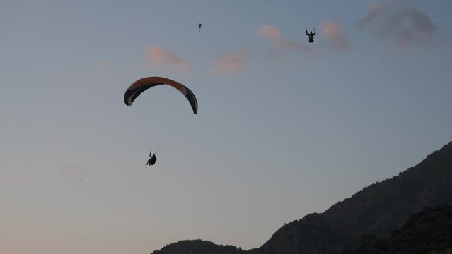 Multi-coloured paragliders circling in the blue sky. Paragliding is the recreational and competitive adventure sport of flying paragliders. &Ouml;l&uuml;deniz, Fethiye, T&uuml;rkiye