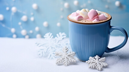 Obraz na płótnie Canvas Warm cocoa in a blue mug topped with pink and white marshmallows, set against a snowy background with delicate snowflakes.