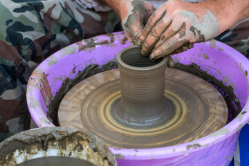 Hands of a potter, creating an earthen jar on the circle.