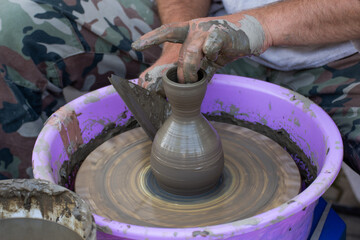 Hands of a potter, creating an earthen jar on the circle.