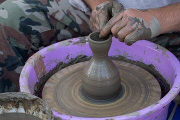 Hands of a potter, creating an earthen jar on the circle.