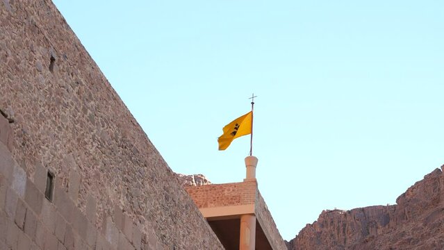 Zoom shot of the flag with the two-headed eagle of the Byzantine empire in Saint Catherine Monastery roof. Ancient historical religious place at Mount Sinai. Tourist excursion to the Mountain of Moses