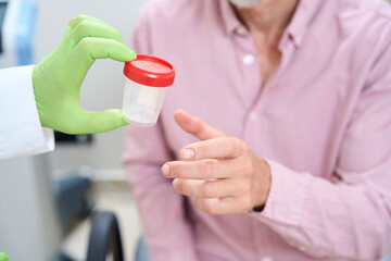 Medical worker gives a man container for collecting urine test © Svitlana