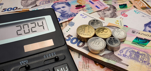 New year 2024 in Ukraine. War and crisis. Calculator on the background of Ukrainian hryvnia...