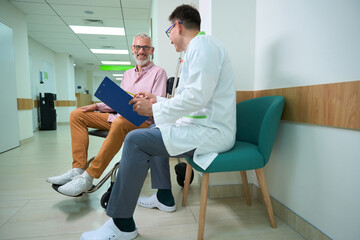 Attending physician in a medical gown conducts questionnaire on patient