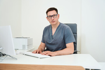 Fototapeta premium Doctor works at a computer in the workplace