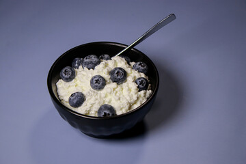 Close up of cottage cheese with fresh blueberries in black bowl, hight protein dessert