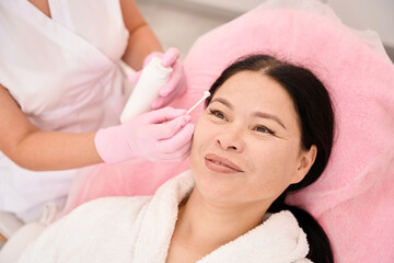 Obraz na płótnie Canvas Beauty master applies cream to the clients eyebrows