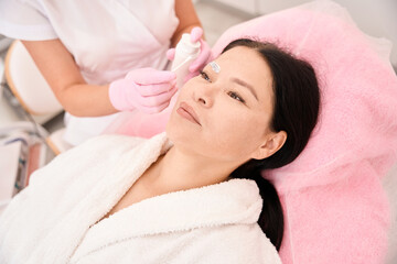 Obraz na płótnie Canvas Beauty master applies cream to a woman eyebrows with applicator