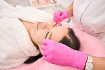 Esthetician doctor marks clients eyebrows before procedure with special thread