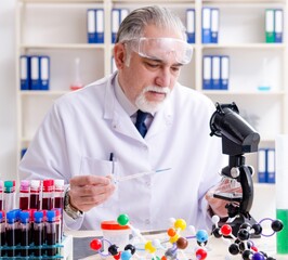 Old male chemist working in the lab