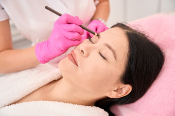 Obraz na płótnie Canvas Marking a woman eyebrows before the procedure