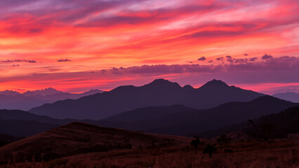 Sonnenuntergang in den Bergen: Rote, rosa und orange Himmel über lila Gipfeln