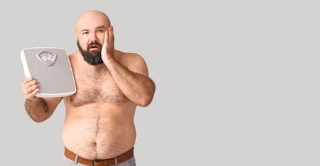 Fototapeta premium Overweight man holding scales on grey background with space for text. Weight loss concept