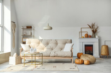 Interior of light living room with electric fireplace, couch and pumpkins