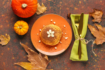 Plate of tasty pumpkin pancakes with cocoa powder and seeds on grunge background