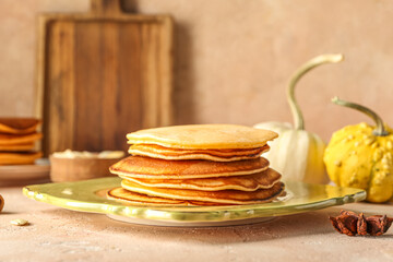 Plate with tasty pumpkin pancakes and star anise on beige background