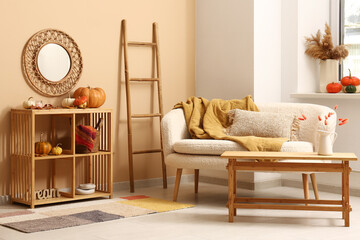 Interior of stylish living room with white sofa, coffee table and pumpkins on shelving unit