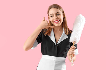 Beautiful female janitor with pp-duster showing "call me" gesture on pink background