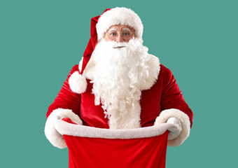 Santa Claus with bag full of Christmas gifts on turquoise background