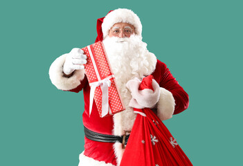 Santa Claus with bag and Christmas gift on turquoise background