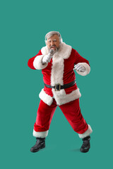 Cool Santa Claus in headphones with microphone singing Christmas song on turquoise background